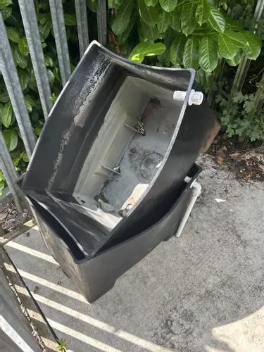 Original plastic inlet water tanks removed from a cold pressure washer system after deforming due to constant hot water feed. The unsealed design also caused condensation buildup inside the cabinet, leading to poor hygiene and reliability issues.